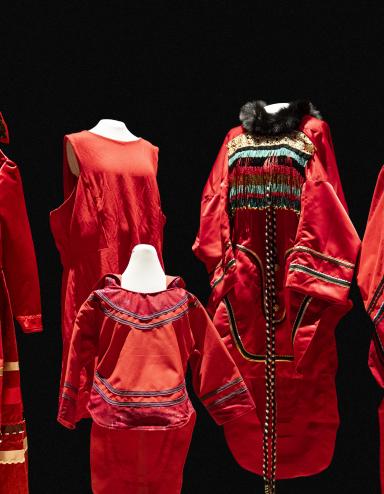 5 red dresses of different sizes and designs are displayed on mannequins. Partially obscured.