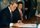 Brian Mulroney sitting and signing a document. Art Miki is sitting beside him looking on.