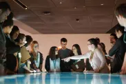 A group of young people stand around an interactive table emitting blue and white light.