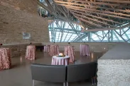 A Tyndall stone terrace is decorated for a reception with light pink satin tablecloths covering cocktail tables and brown leather sofas.