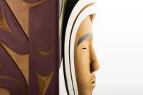 A closeup of a carved wooden box, showing the carved face of a person against a white background.