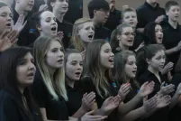 About two dozen youth singing in a choir.