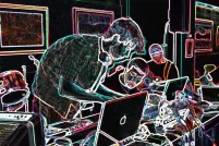 Four people around a table covered in computers and electronic music equipment. The photo has been altered so that the background is black and the elements of the photo are outlined in multi-coloured neon.