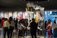 A large number of people in a gallery examining a display comprised of several seemingly ordinary objects