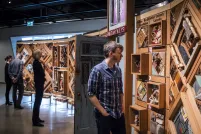 Two people look at a large artwork consisting of objects set in cedar frames, with an open door in the middle.
