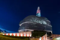 A building adorned with projected red-and-white stripes, topped by a glowing red tower.
