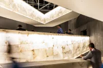 A crowd of people walk along illuminated ramps. Some are taking photographs.