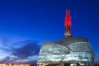 An unusual museum building topped by a glowing red tower.