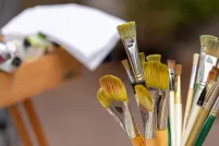 Artists’ paintbrushes of various sizes, lengths and colours in a metal container.