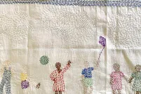 A piece of stitched fabric portraying families in diverse cultural clothing engaged in happy activities.