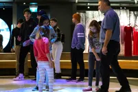 A crowd of people in a museum gallery. There are colourful light bubbles on the floor beneath them.