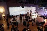 A crowd of people watches a band play on a brightly lit stage.