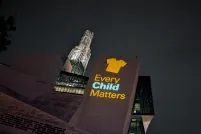 An image of an orange shirt with the text Every Child Matters is projected on an exterior wall of the Museum.
