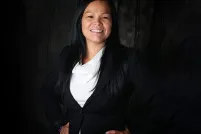 A smiling woman faces the camera with her hands on her hips.