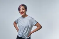 A smiling woman with purple hair wearing a t-shirt.