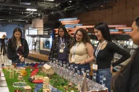 A group of students stand around a diorama displayed on a table in a museum gallery.