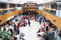 Many people gathered in an open indoor space with tables and posters set up on them.