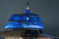 The exterior of the Canadian Museum for Human Rights is pictured at night. The building is lit up from the inside with vibrant deep blue lights.