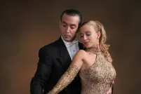 A man and woman dressed in formal attire pose with an accordion.