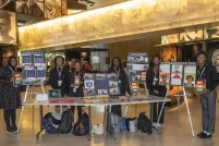 Six black students in a museum hall present proudly their work on posters and on a table.