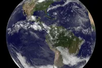 A full view of Earth from space centred on North and South America, with swirling white clouds over blue oceans and green/brown landmasses.