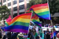 Two large Pride flags waving proudly in a large crowd.