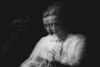 Black-and-white photo of Sarah Harmer playing guitar. It appears like two fuzzy images are juxtaposed one on another.