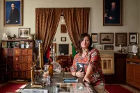 A woman kneels beside a coffee table surrounded by books and heirlooms.