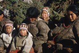 A group of women and children sitting together. The two children in the front are looking at the camera.