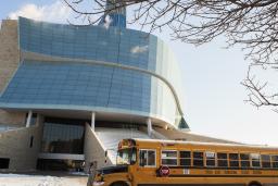A yellow school bus is parked in front of the Museum. 