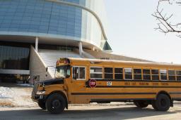 A yellow school bus is parked in front of the Museum. 