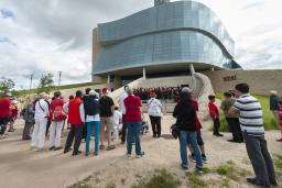 A group of people watching a choir as they perform on the Museum’s exterior amphitheater.