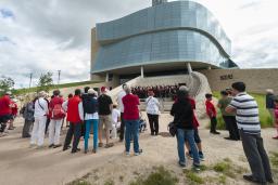 A group of people watching a choir as they perform on the Museum’s exterior amphitheater. 