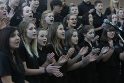 About two dozen youth singing in a choir.