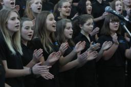 About two dozen youth singing in a choir.