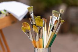 Artists’ paintbrushes of various sizes, lengths and colours in a metal container.