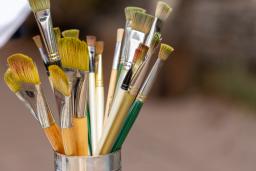 Artists’ paintbrushes of various sizes, lengths and colours in a metal container.