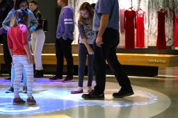 A crowd of people in a museum gallery. There are colourful light bubbles on the floor beneath them.