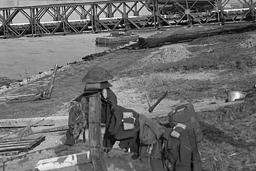 A group of armed soldiers watch a tank drive past.