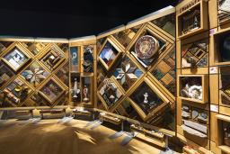 A large art installation composed of hundreds of objects embedded in a cedar frame resembling a quilted blanket.