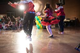 Three dancers in red and white outfits perform in front of a crowd of children at the Canadian Museum for Human Rights.