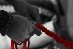 Two hands in black and white hold onto a red rope.