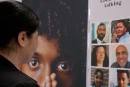 A woman gazes at a display showing faces of a diverse group of people.