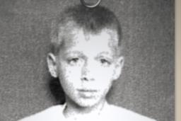 A black-and-white photo of a sad-looking boy is paperclipped to an institution admission form that asks his name, when he was admitted, and his mental condition.