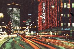 Late 1960s-era photo of downtown Winnipeg showing the Eaton’s building decorated with many bright Christmas lights.