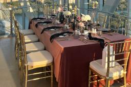 Nestled in a corner of the observation platform of the glass tower is a lavishly decorated table with burgundy tablecloth, floral arrangements and dinnerware, and gold chairs.