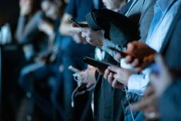 A group of people using cell phones while standing.