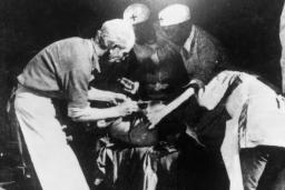 Four people standing around an operating table.