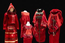 Cinq robes rouges de tailles et de modèles différents sont exposées sur des mannequins.