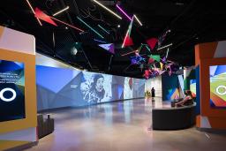 A museum gallery featuring artwork projected onto large screens and colourful geometric shapes.